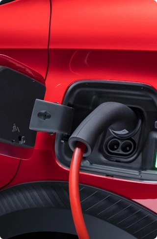 Zbliżenie gniazda ładowania w Citroënie ë-C3 Van z podłączonym przewodem ładowania, ilustrujące elektryczną mobilność i wygodę ładowania.