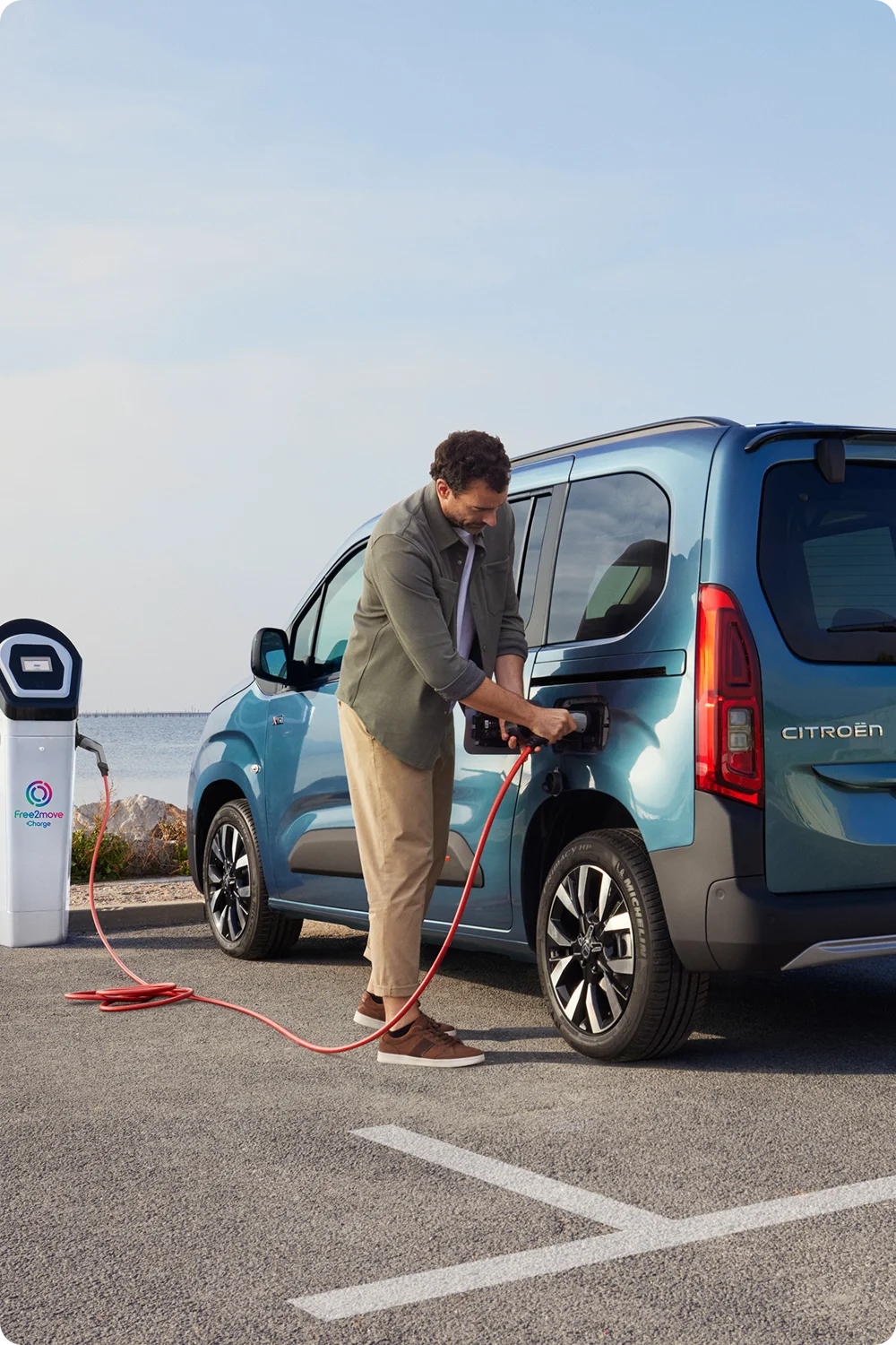 Widok z boku ë-Berlingo ładowanego na stacji Free2move pokazujący bezpieczeństwo, efektywność, technologię oraz pewne użytkowanie elektryczne
