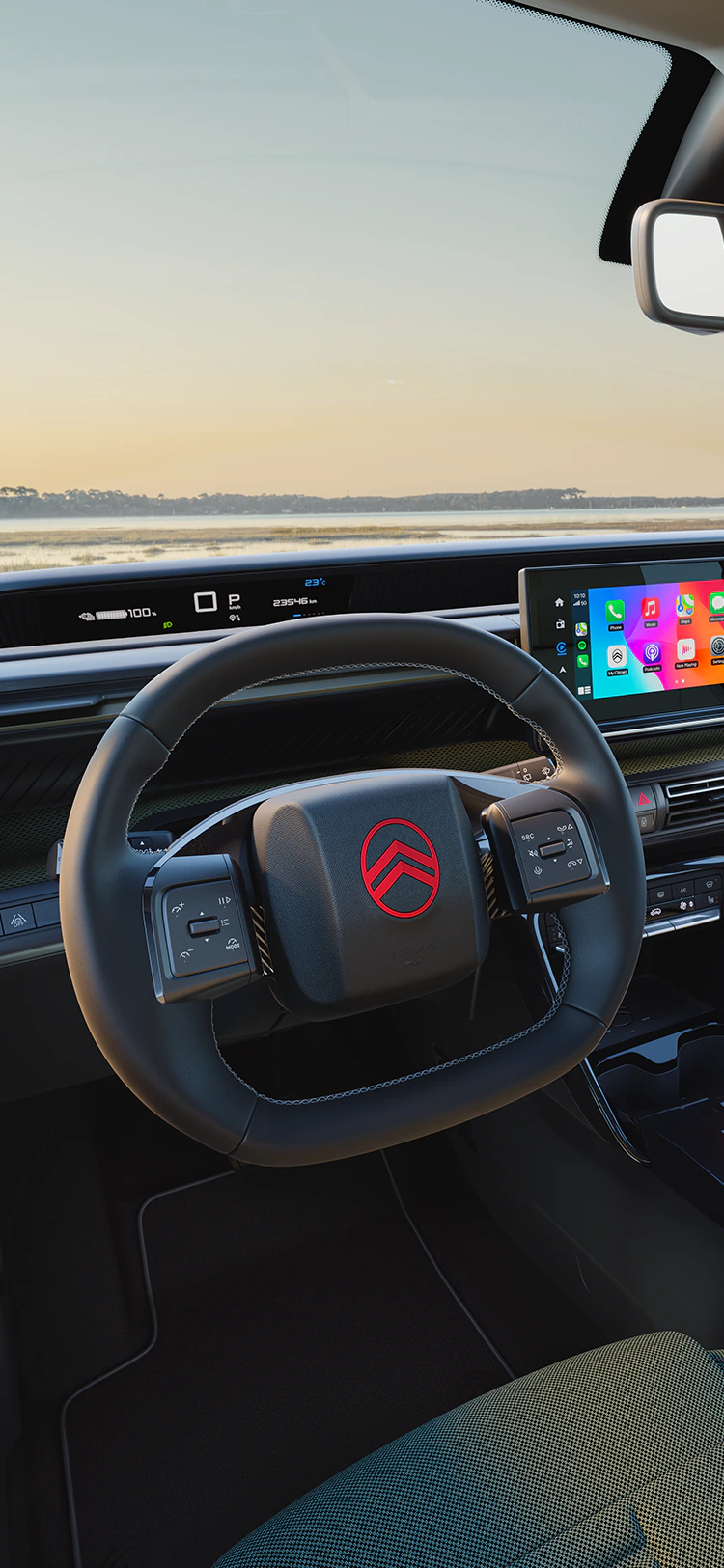 Widok z miejsca kierowcy na deskę rozdzielczą Citroëna C3 Outdoor z ekranem systemu multimedialnego, ukazujący łączność i komfort Advanced Comfort podczas rodzinnych podróży SUV-em