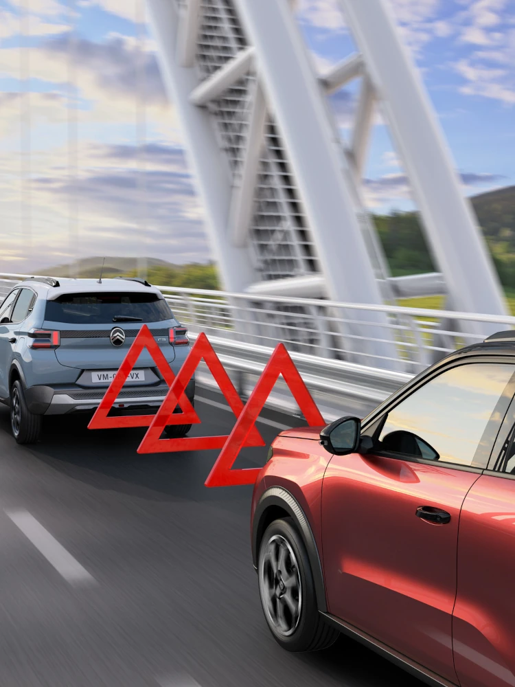 Widok jazdy z tyłu kompaktowego SUV-a Citroëna C3, ilustrujący system ostrzegania przed kolizją czołową dla bezpieczniejszej, pewnej i przystępnej mobilności miejskiej.