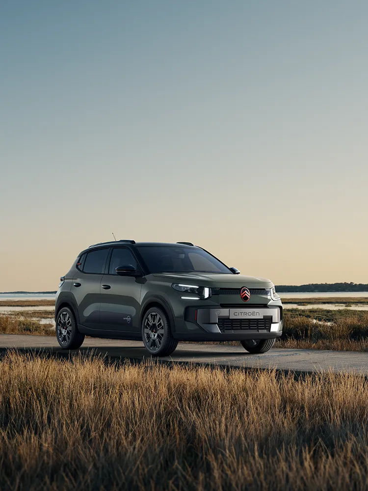 Widok Citroëna ë-C3 Outdoor z przodu pod kątem 3/4, z charakterystycznymi światłami LED, ukazujący komfort Advanced Comfort w otoczeniu nadmorskich mokradeł