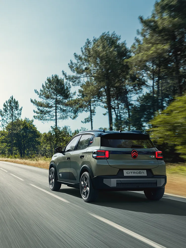 Widok Citroëna ë-C3 Outdoor z tyłu pod kątem 3/4, z tylnymi światłami LED, ukazujący komfort Advanced Comfort podczas jazdy otwartą drogą