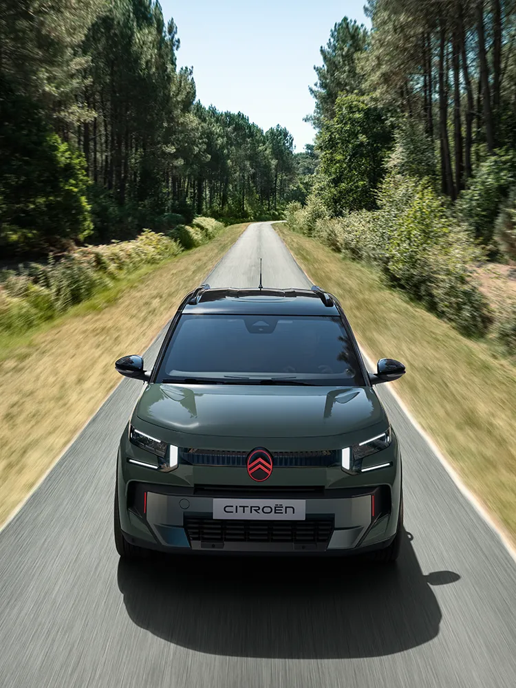 Widok Citroëna ë-C3 Outdoor z góry od przodu, z charakterystycznymi światłami LED, ukazujący komfort Advanced Comfort podczas jazdy leśną drogą