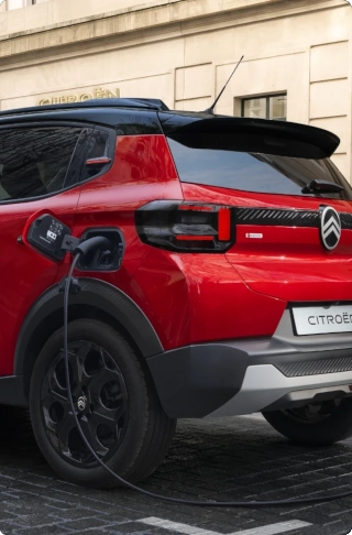 Ujęcie z tyłu pod kątem 3/4 elektrycznego SUV-a Citroëna ë-C3, ukazujący łatwy dostęp do portu ładowania dla praktycznej, efektywnej i przystępnej mobilności miejskiej.