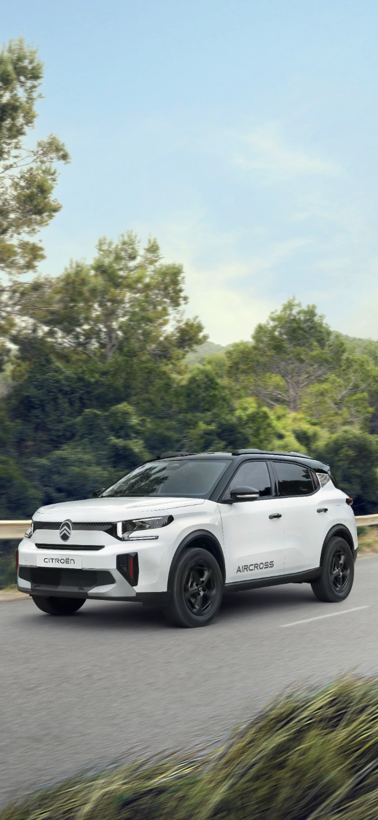 Widok z przodu pod kątem 3/4 podczas jazdy elektrycznego SUV-a Citroëna ë-C3 Aircross podkreślający pewną obecność na drodze dla płynnej, wydajnej i przystępnej mobilności.