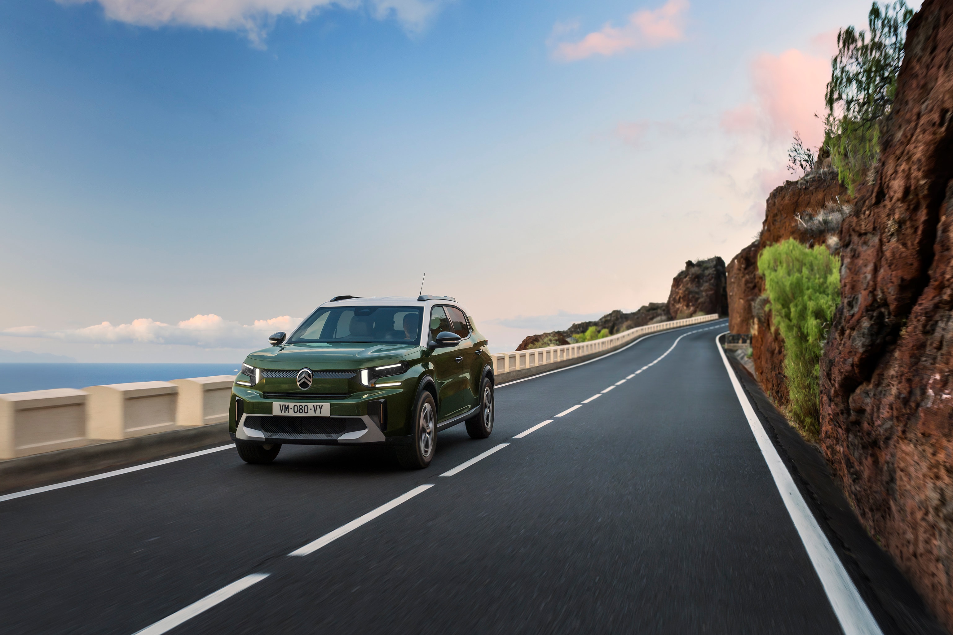 Widok z przodu pod kątem 3/4 podczas jazdy SUV-a Citroëna C3 na malowniczej drodze podkreślający zwinną, pewną i przystępną mobilność na co dzień.