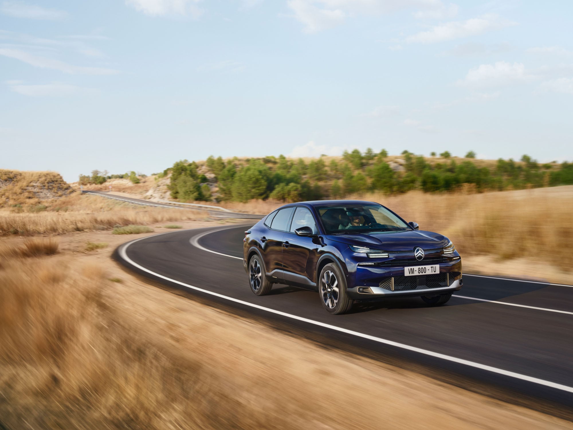 Widok z przodu pod kątem 3/4 podczas jazdy Citroëna C4 X pokazujący zwinną sylwetkę fastback dla pewnej i przystępnej mobilności.