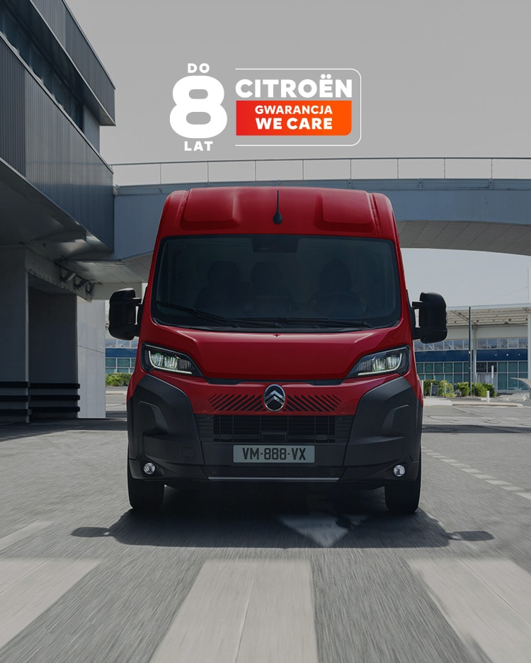 Widok z przodu czerwonego dostawczego Citroëna Jumper, jadącego ulicą nowoczesnego miasta, podkreślający solidną konstrukcję, praktyczność i wyrazisty wizerunek na drodze.